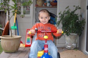 Evan on tricycle he got for being potty trained, and sporting haircut thanks to Daddya and Matthew